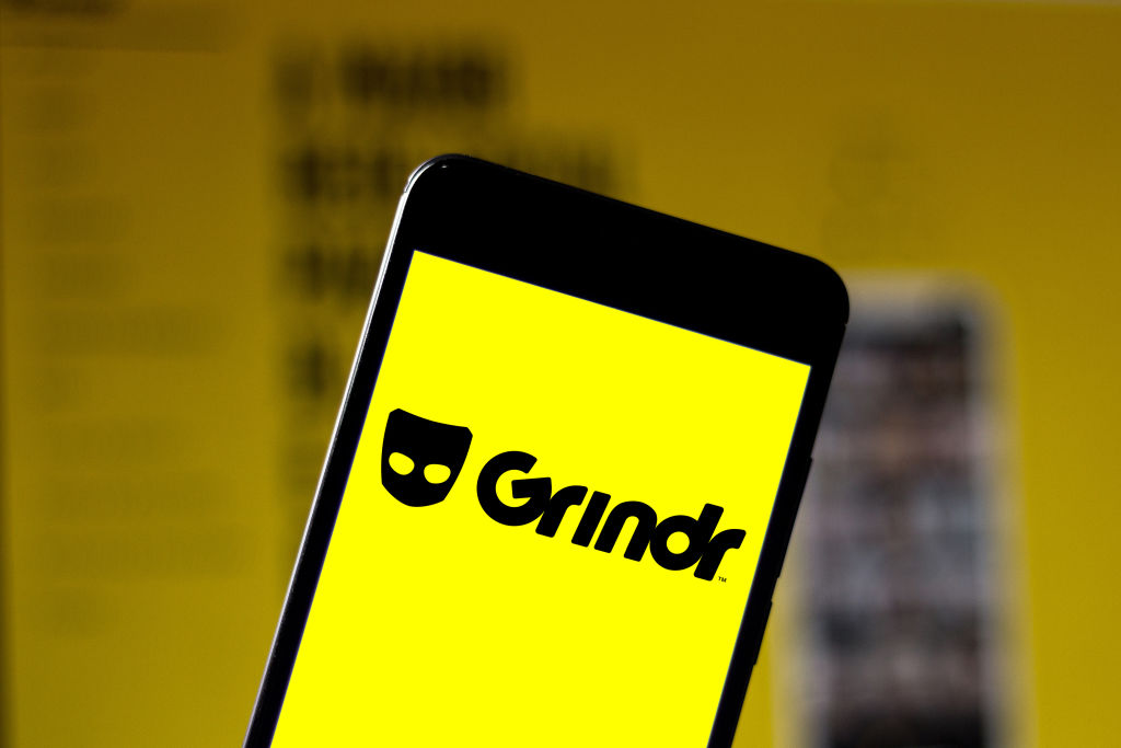 A phone showing a bright yellow screen and the word Grindr