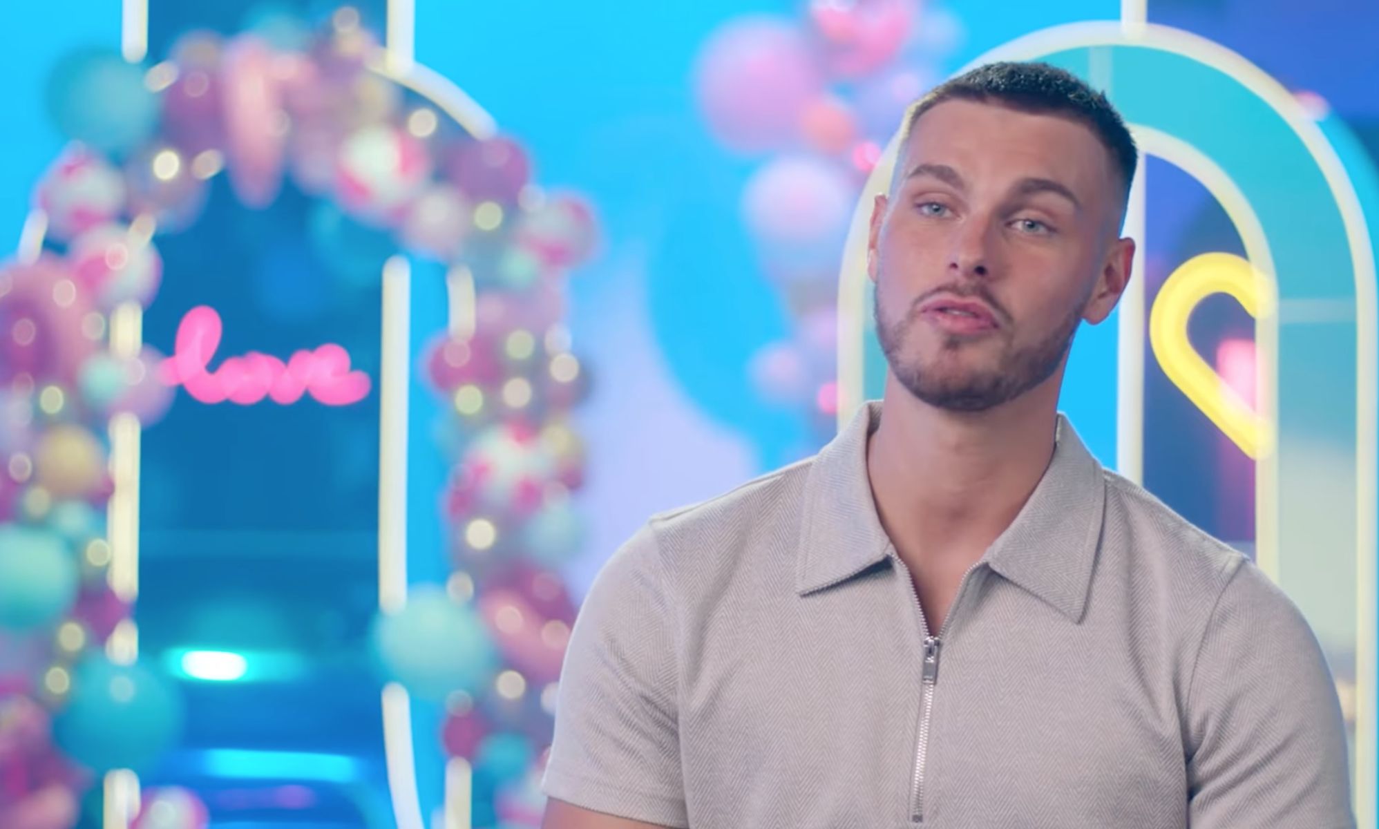 Love Island 2023 contestant George Fensom wears a grey shirt as he sits down for an interview
