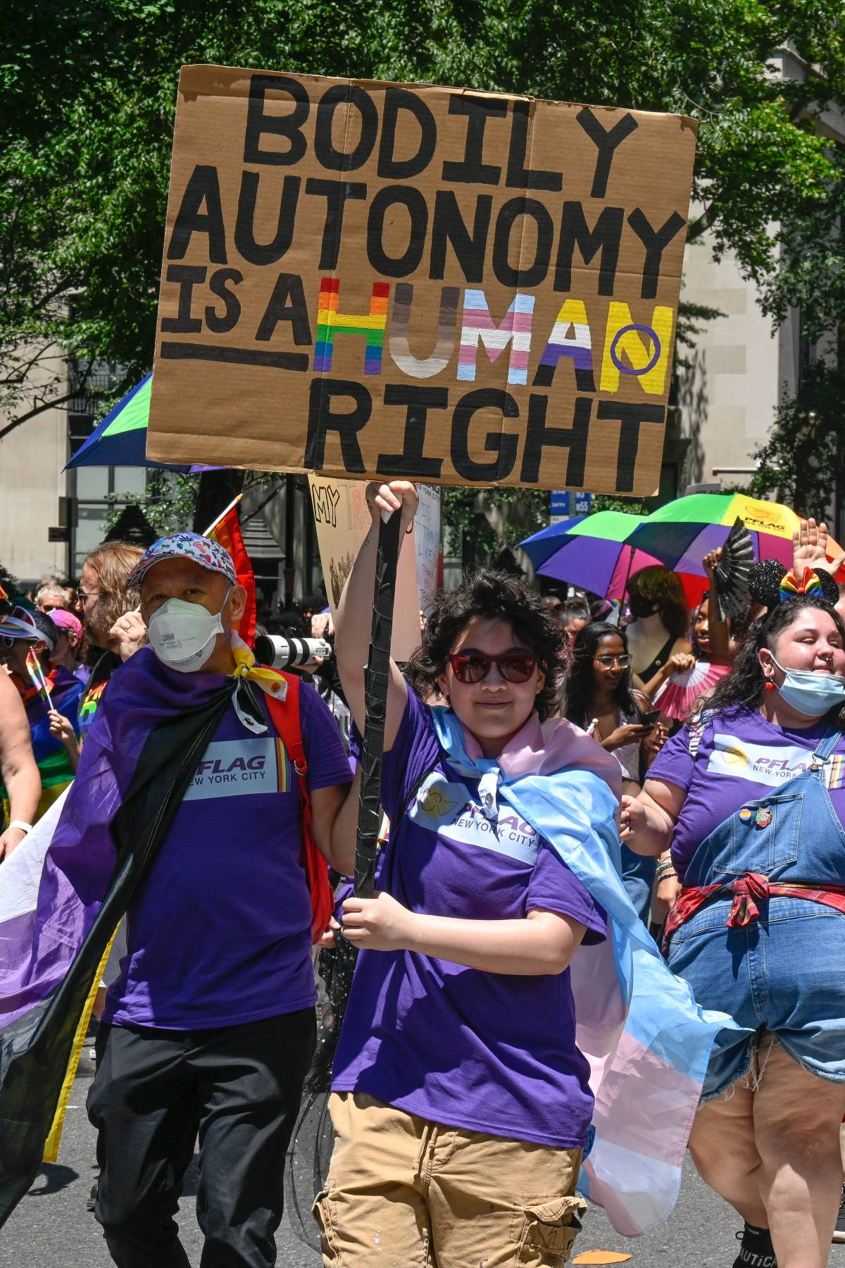 A person wearing a purple shirt holds up a sign reading 