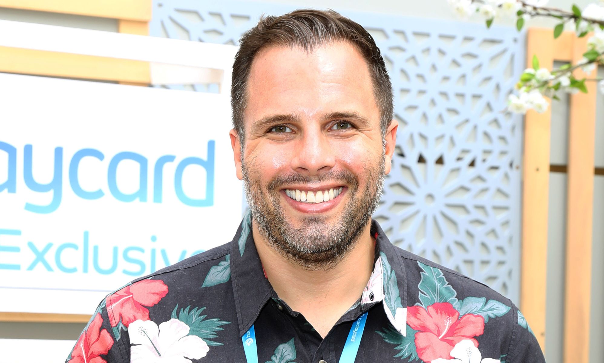 Dan Wootton, in a Hawaiian shirt, smiles towards a camera.