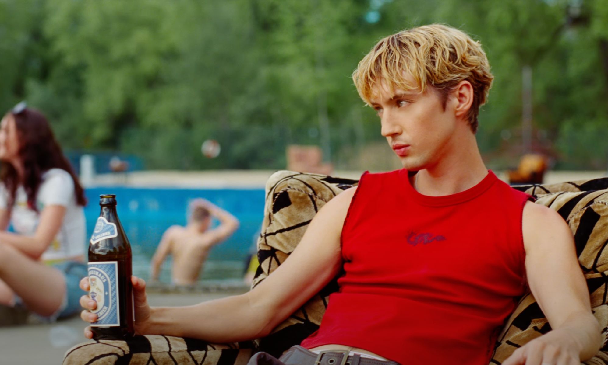 Troye sivan in a red vest and leather chaps in the new Rush music video.