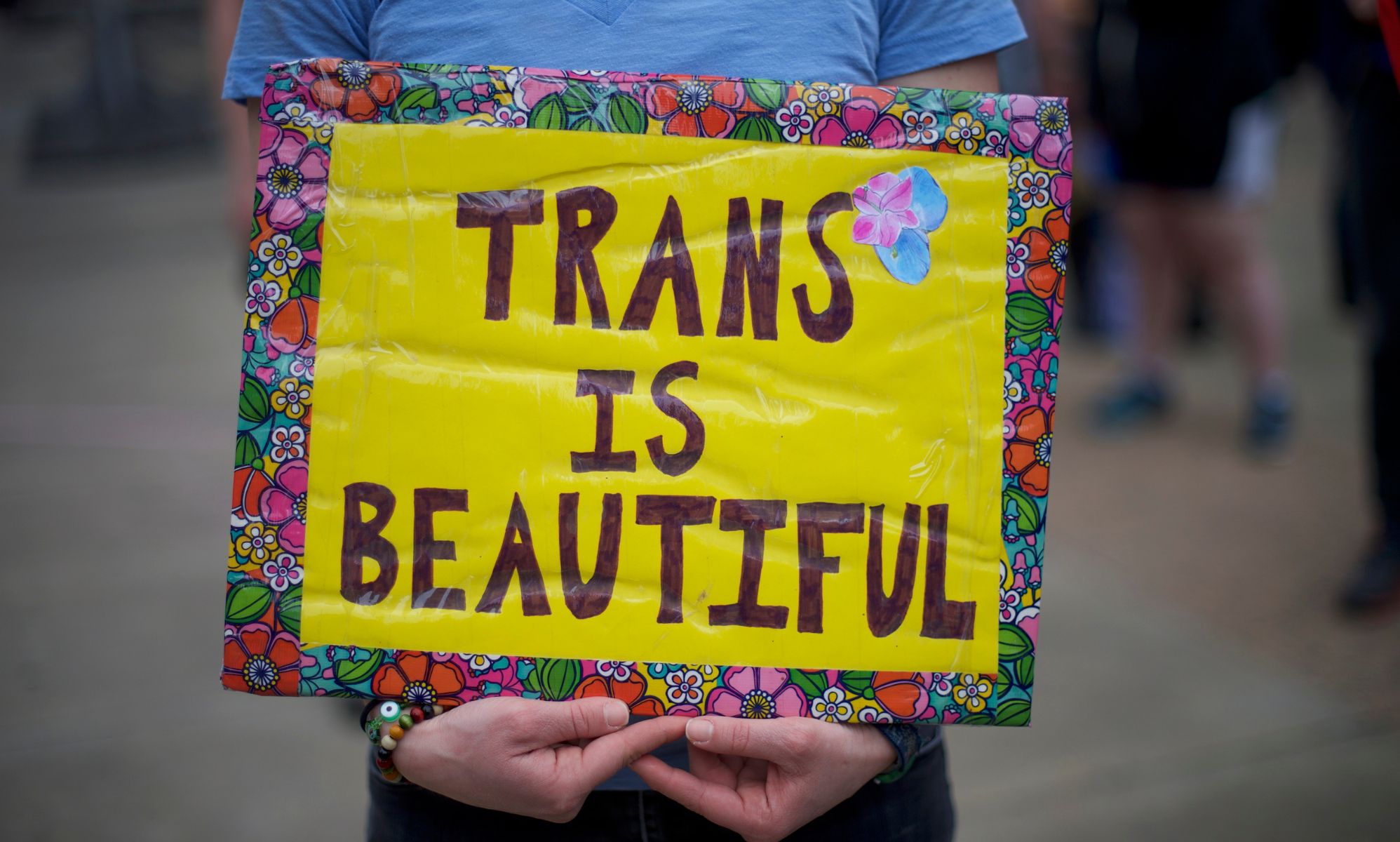A person holds up a sign reading &quot;trans is beautiful&quot; during a demonstration in support of the trans community and lambasting anti-trans policies like bathroom bans, bans on gender-affirming healthcare and more