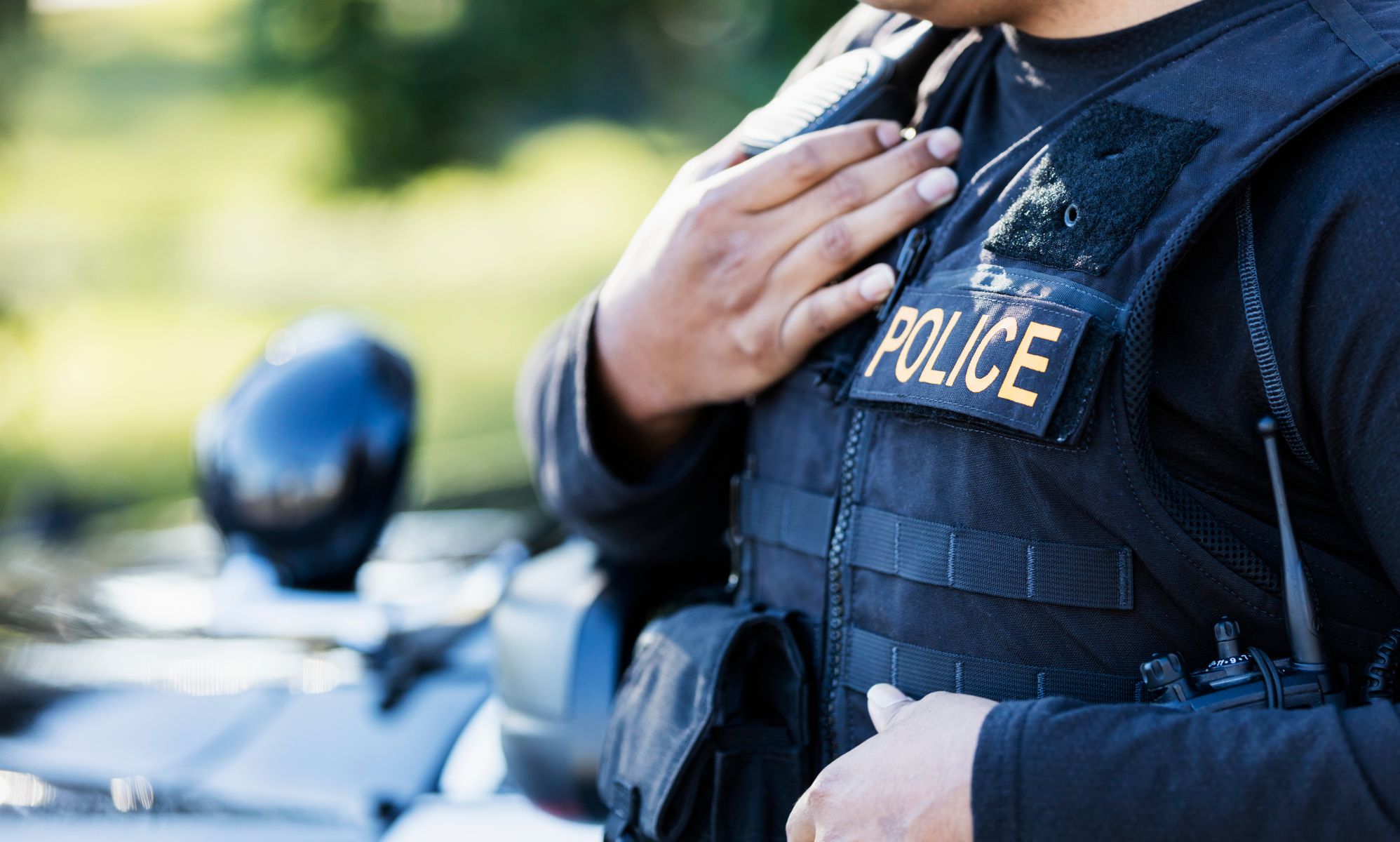 A police officer wearing a vest stood by a police car.