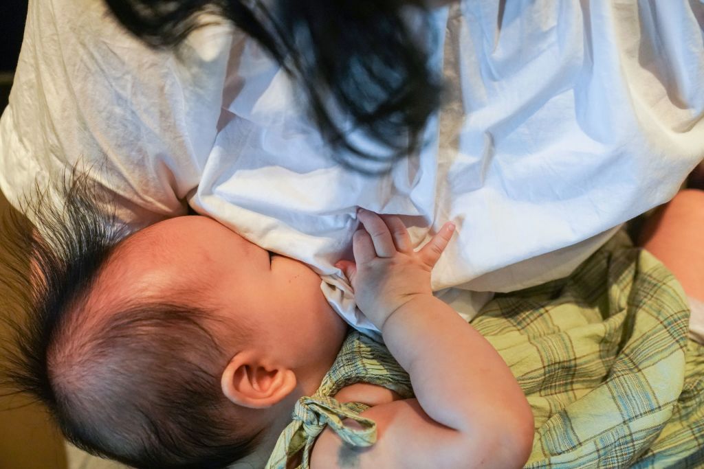 A woman breastfeeds her child in Shanghai. The picture shows a baby drinking milk from their mother