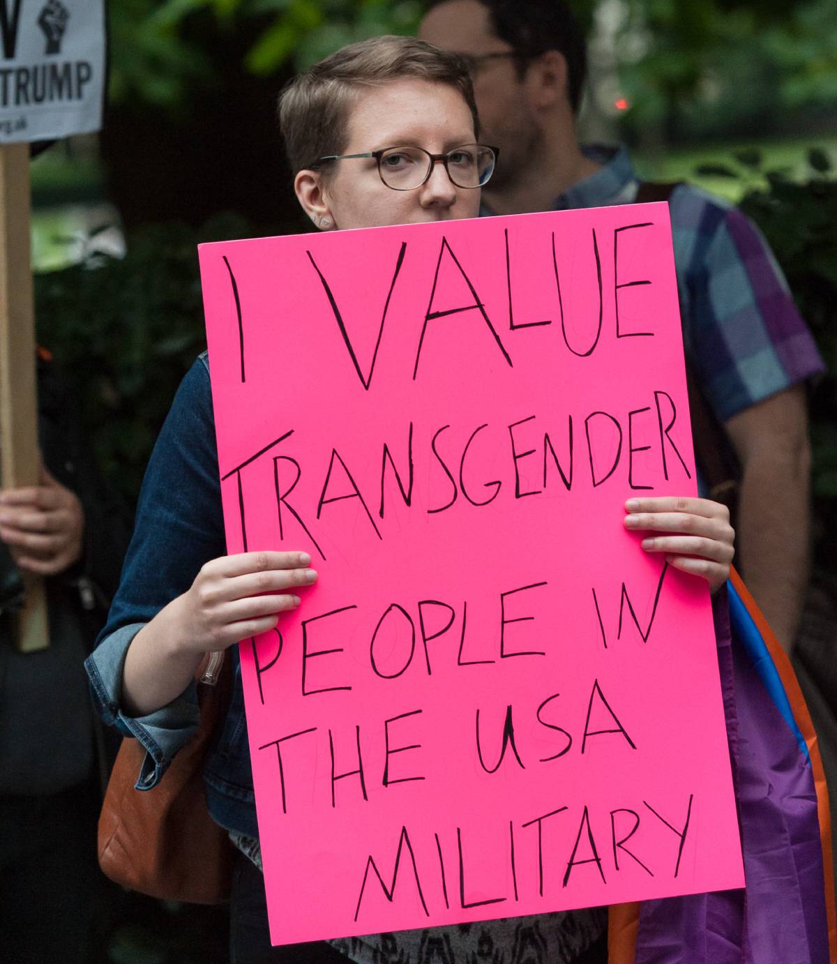 A person holds up a sign reading 