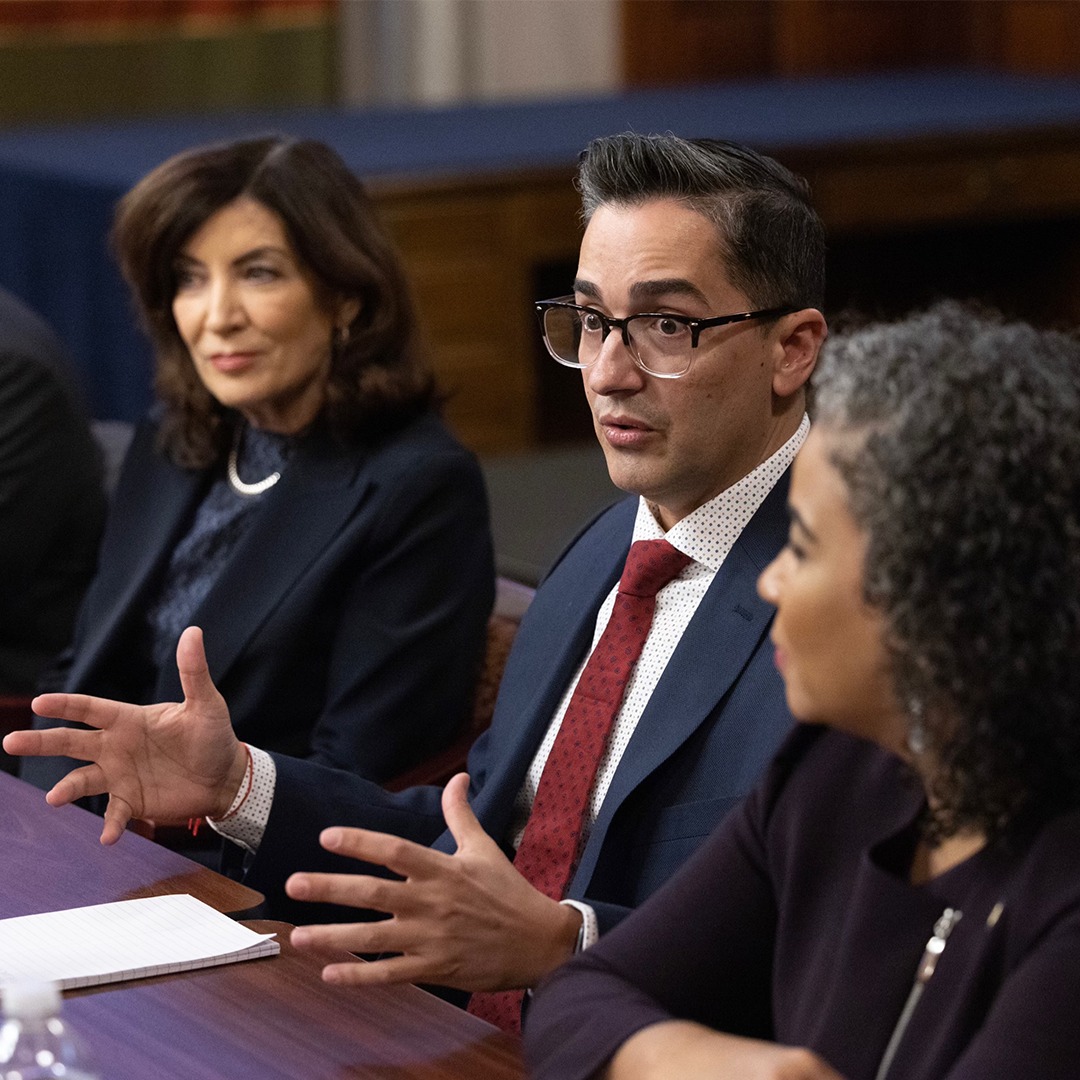 Frankie Miranda, the first openly LGBTQ+ president of the Hispanic Federation, wears a suit and tie as he talks to others at the New York Governor