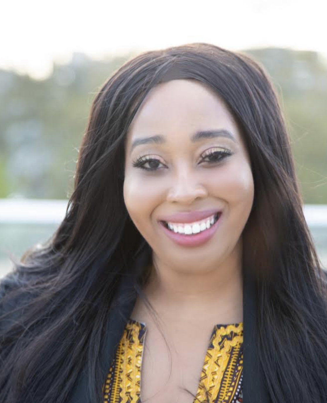 This is in an image of Jacqui Rhule-Dhager. She is wearing a black jacket with a yellow top. 