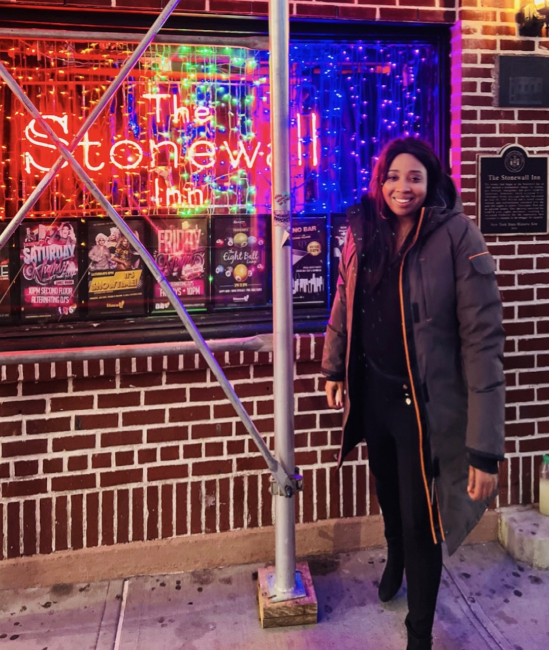 This is an image of a Black woman, Jacqui Rhule-Dagher outside the Stonewall Inn in New York City. 