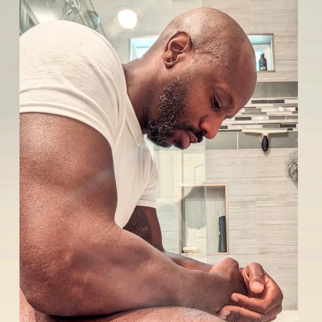 Race Cooper sitting down indoors wearing a white t-shirt. He is pictured in side profile.