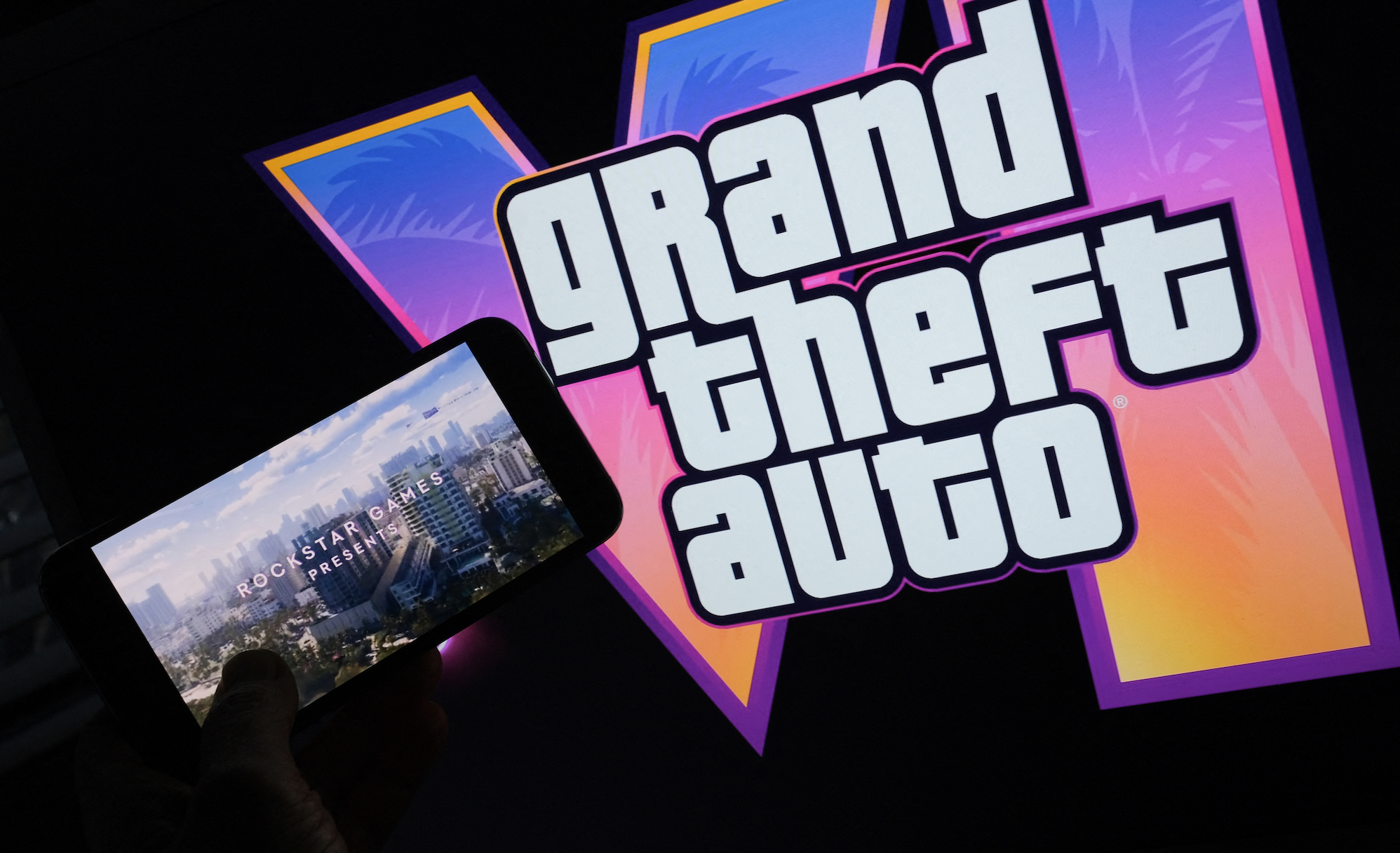 This illustration photo created in Los Angeles, December 4, 2023, shows Rockstar Games’ Grand Theft Auto VI trailer played on a screen in front of the game title. The first trailer for &quot;Grand Theft Auto VI&quot; was officially released ahead of schedule December 4, 2023 due to a leak, touting a 2025 release for the next chapter of the massively successful video game franchise. (Photo by Chris DELMAS / AFP)