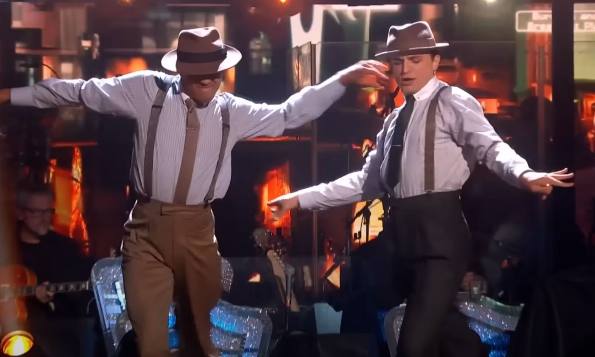Layton Williams and Nikita Kuzmin wear outfits composed of a shirt, suspenders, trousers and hat as they dance together during a performance on BBC