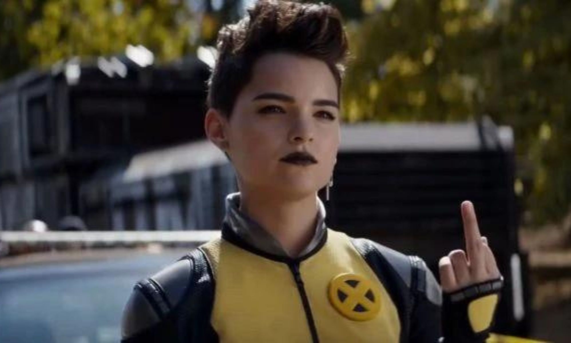 A woman in a yellow and black costume raises her middle finger.