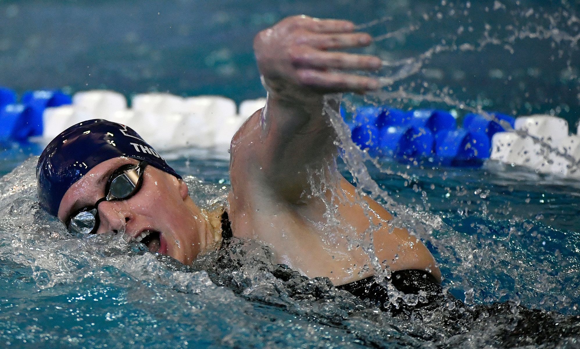 A woman in a swimming pool performing a forward breaststroke.