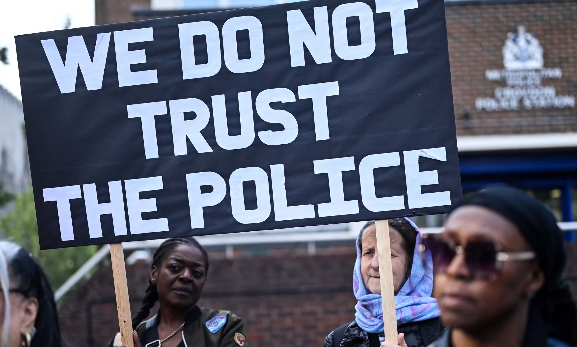 Protestors hold up a sign that reads &quot;we do not trust the police&quot;