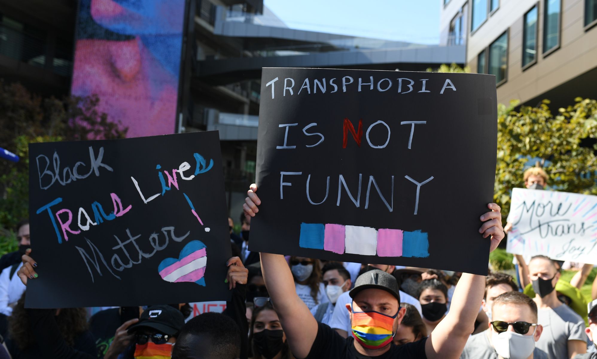 A group of people hold up signs in support of the trans community after Netflix