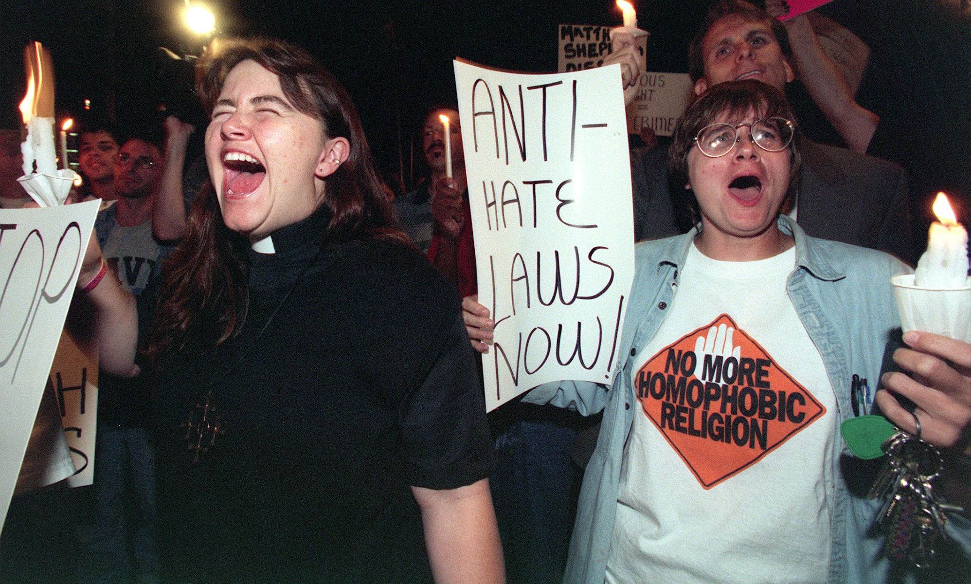 Protestors holding up signs, with one reading &quot;anti-hate laws now&quot; and holding candles dedicated to Matthew Shepard.
