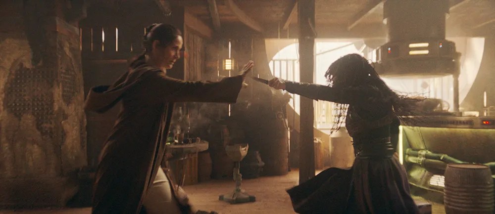 Two jedi battle each other in a dark and hazy room