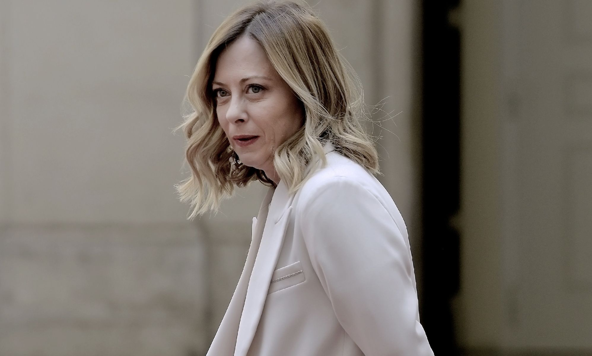 A picture of Giorgia Meloni walking by in a white suit.