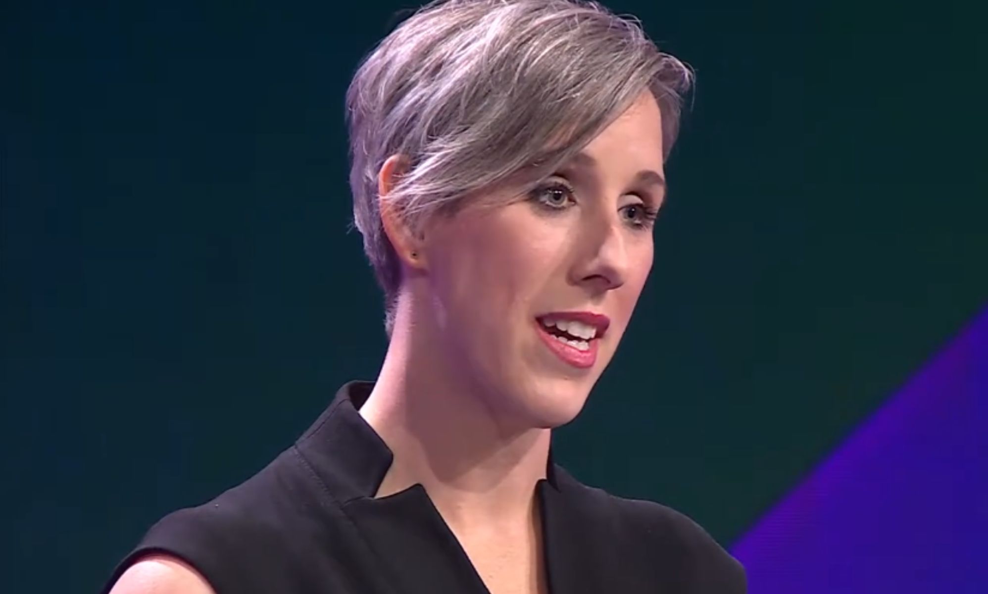 Cathryn Oakley stands in a studio speaking during a presentation.