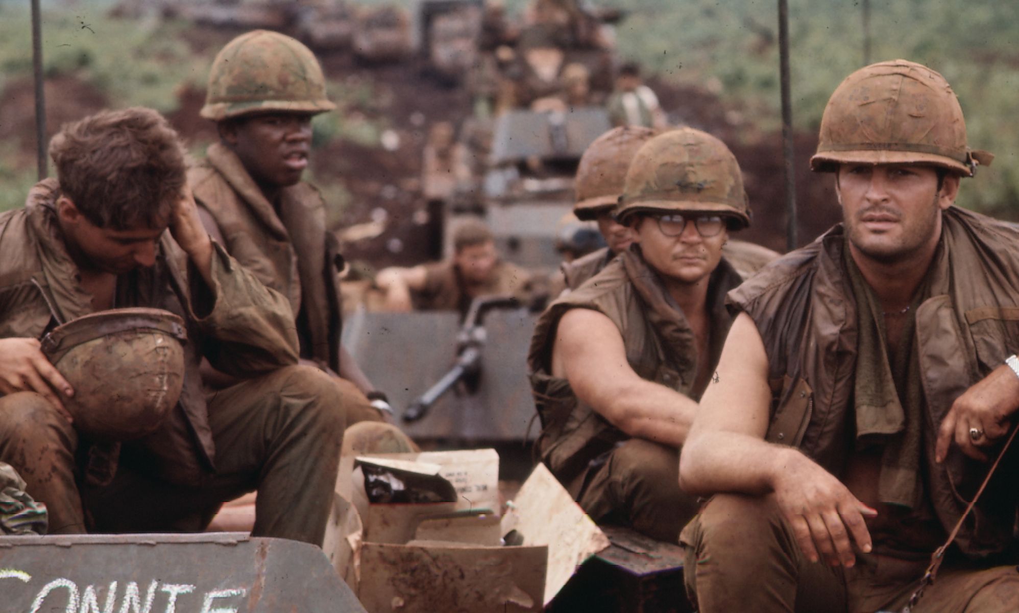 Four Vietnam soldiers sit on top of an APC while crossing the Vietnam border.