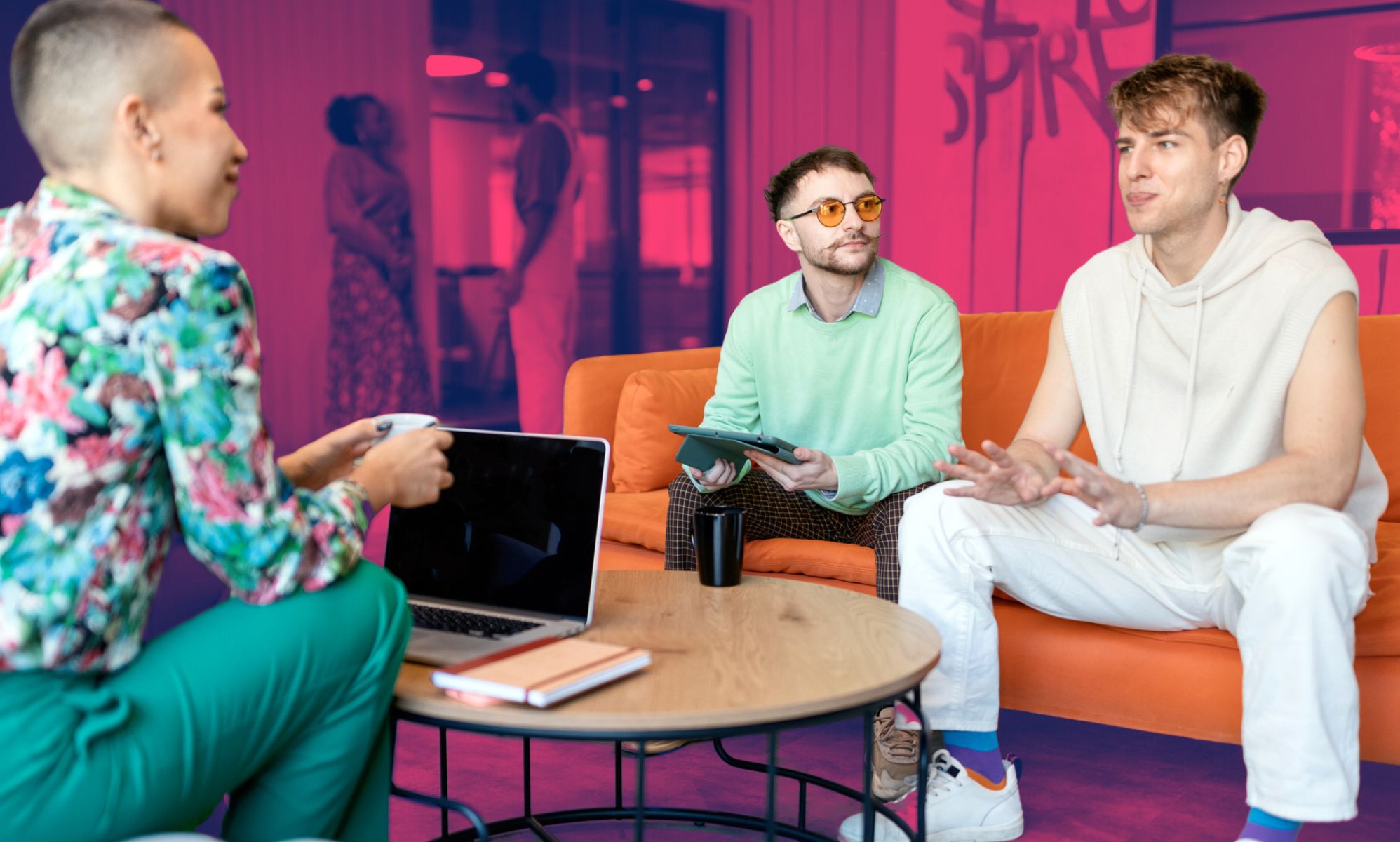 This is an image of 3 Gen employees gathered in a communal area of their office. They are all vibrantly dressed and happily engaging with each other.