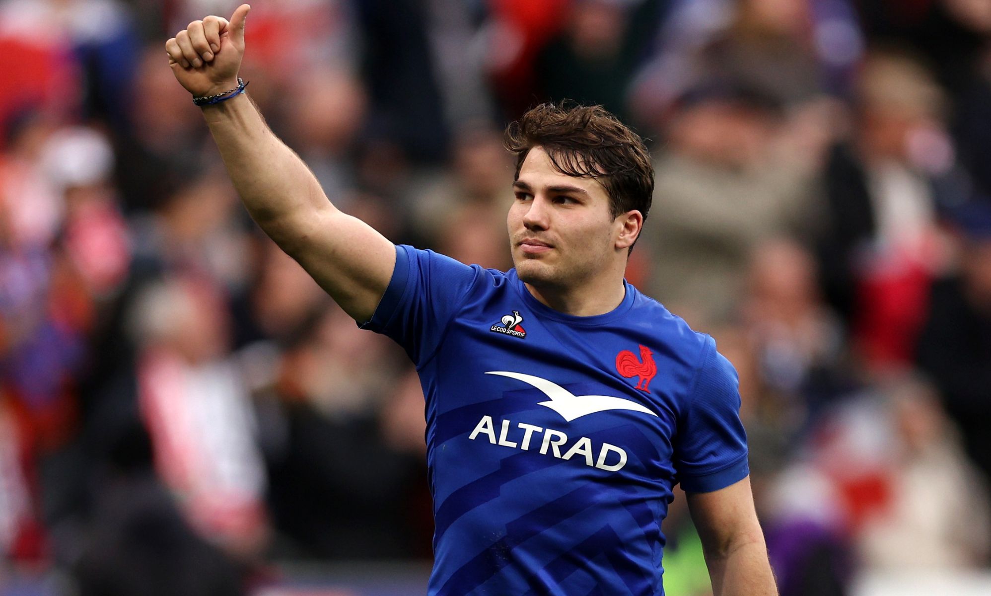 Antoine Dupont with his thumb up to the crowd in a rugby game.