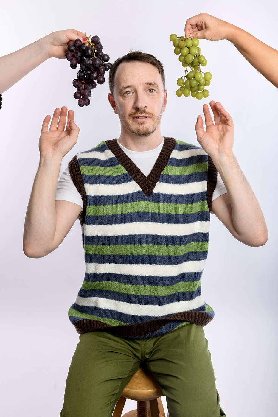 Gearóid Farrelly: Gearóid Rage. Gearóid is sat on a stall with red and whtie grapes about his head. He