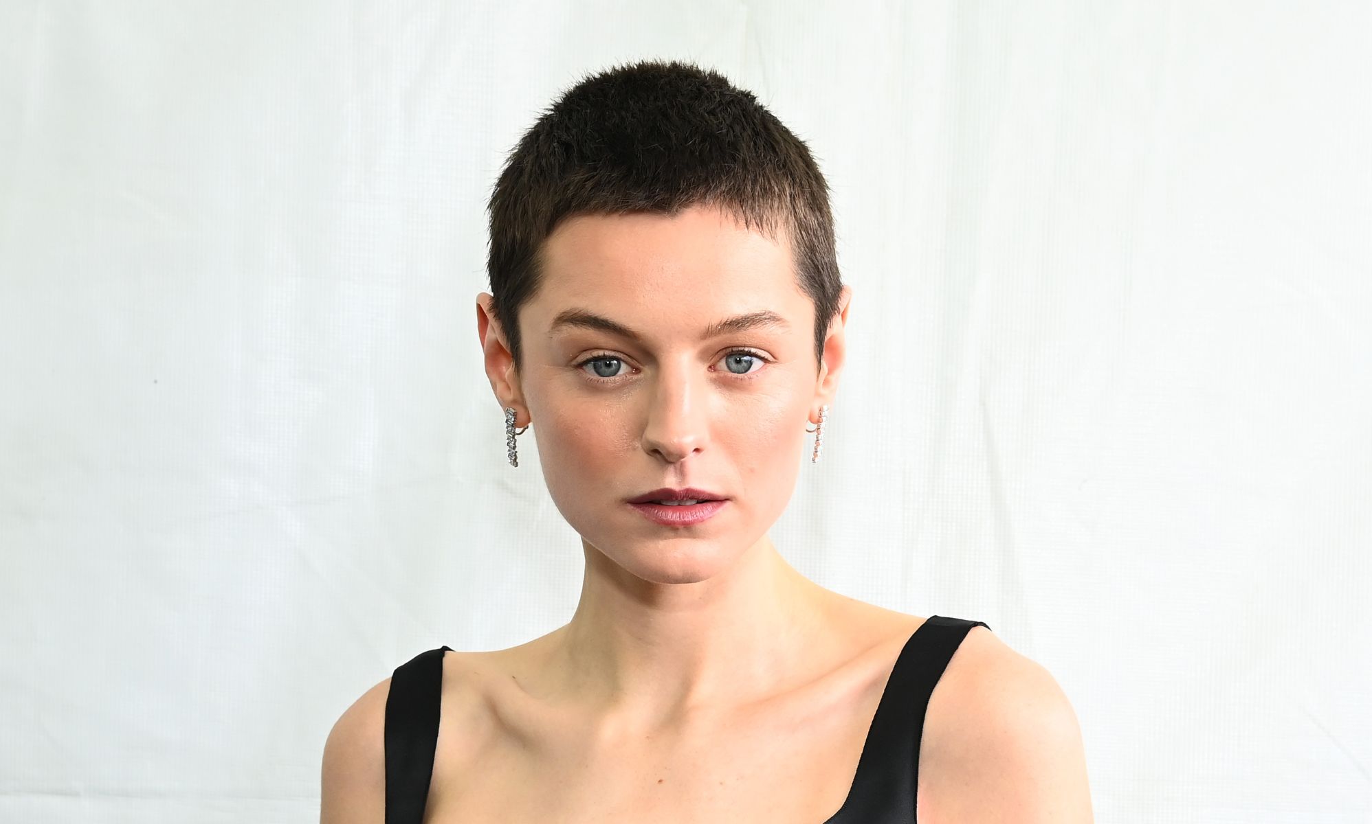 Emma Corrin with cropped brown hair and wearing a strapped black dress at the 2024 Film Independent Spirit Awards.