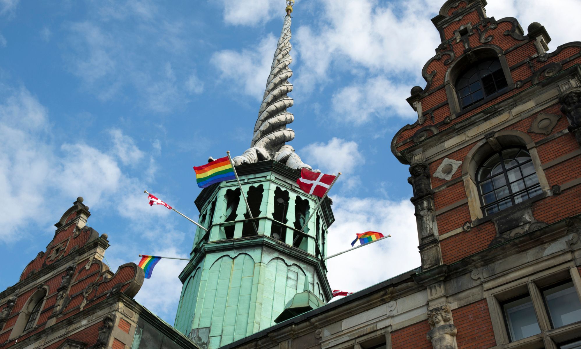 A Pride flag flies along with the Danish flag outside the Børsen, the old stock exchange in Denmark