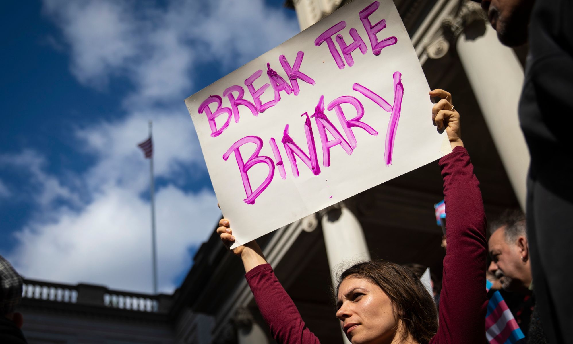 A person holding up a sign that reads &quot;break the binary.&quot;