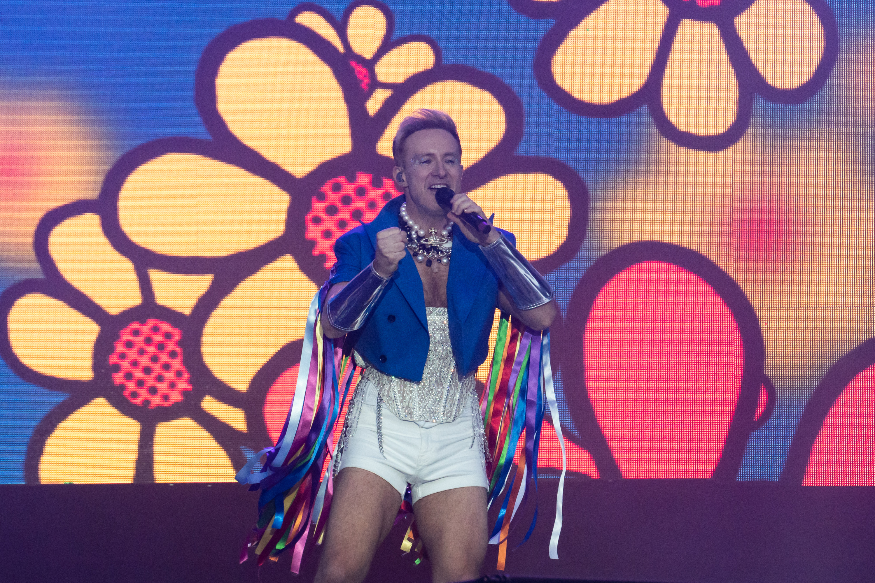 Ian &quot;H&quot; Watkins of Steps performs during the Brighton and Hove 2023 Pride. H is performing with big cartoon flowers behind him. He