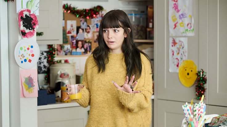 Ramona Marquez as Karen in a yellow jumper in the kitchen