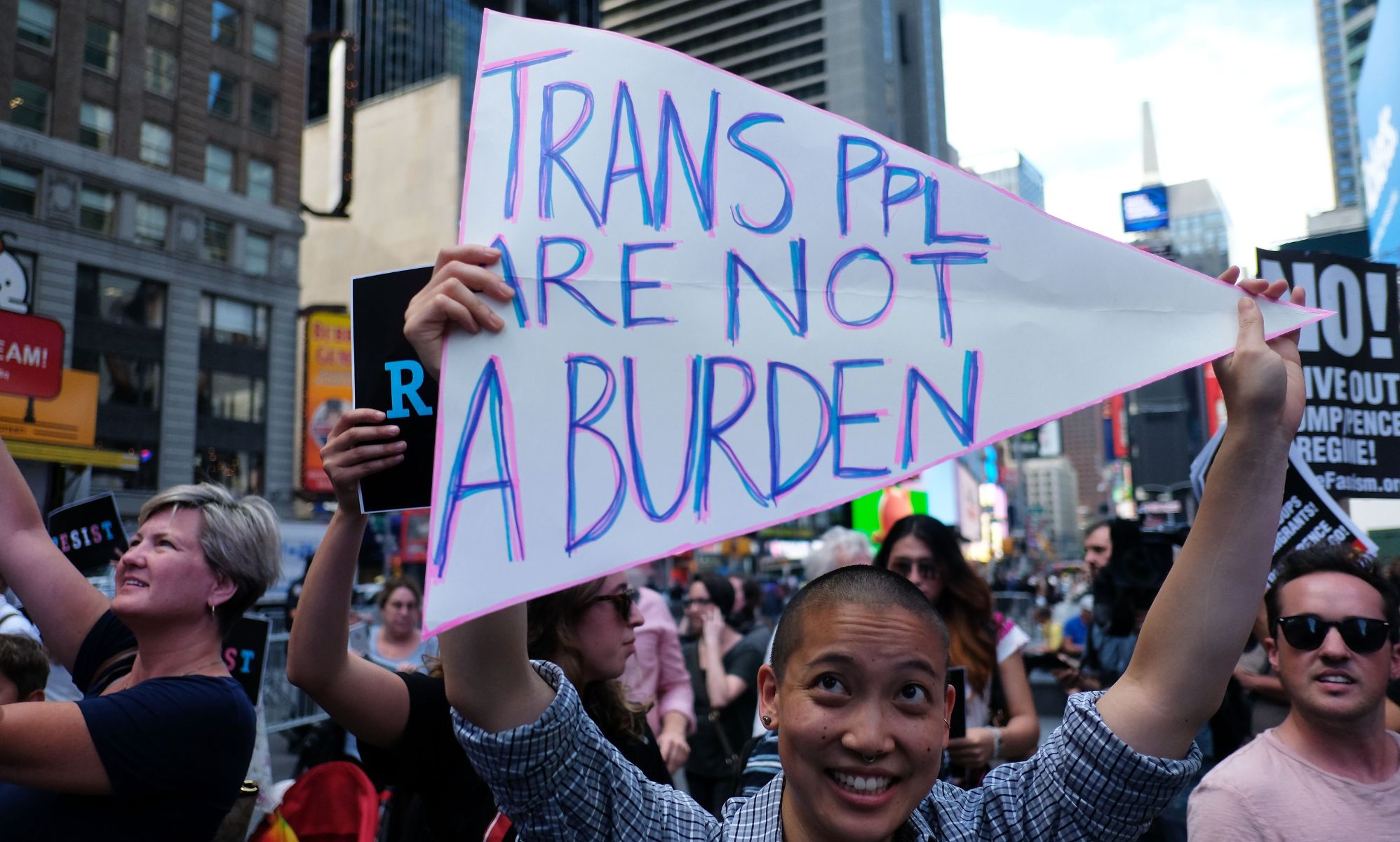 A person holding a sign up that reads &quot;trans ppl are not a burden.&quot;