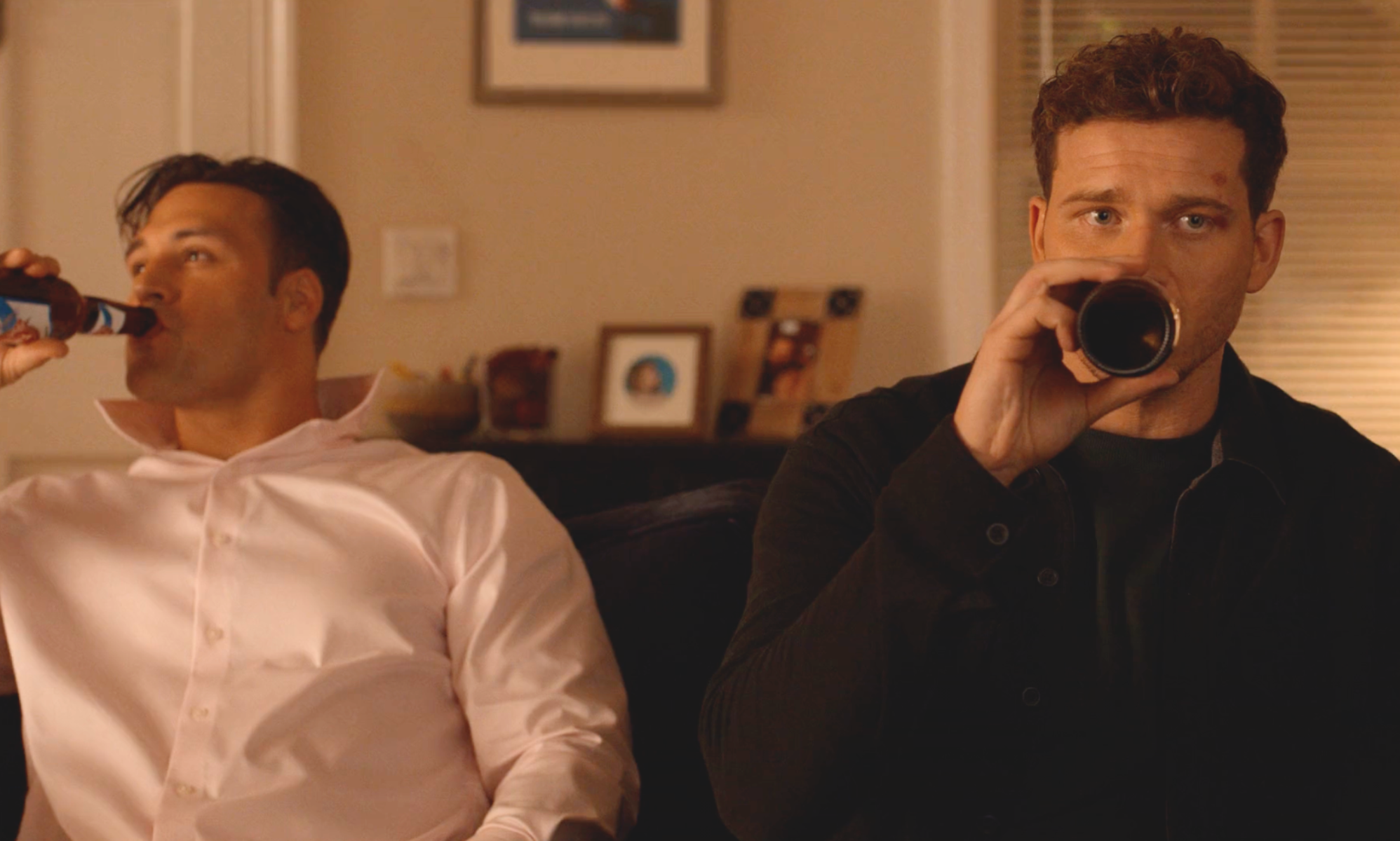 Buck and Eddie drinking beers on a couch together.