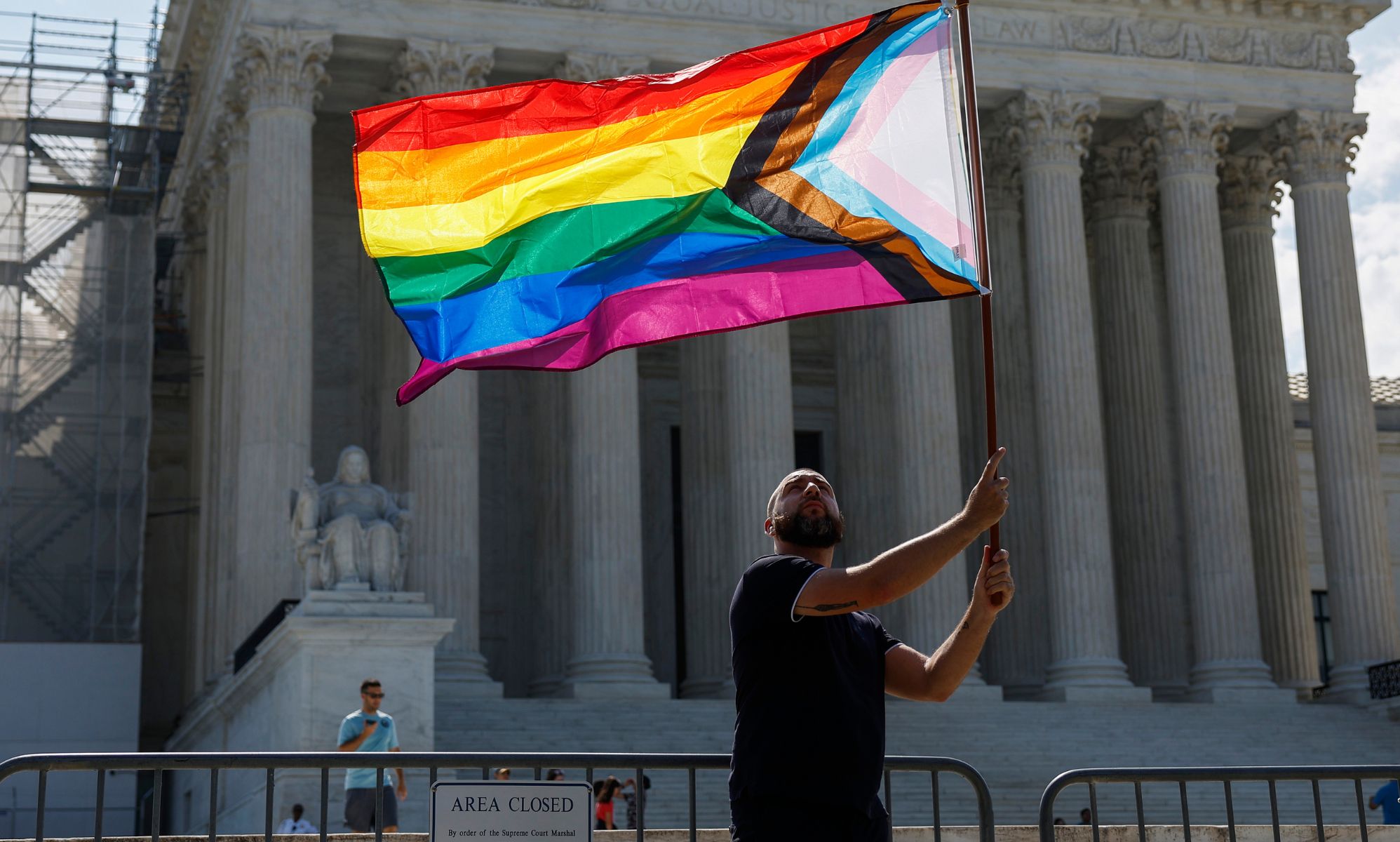 A person waving an LGBTQ+ flag.