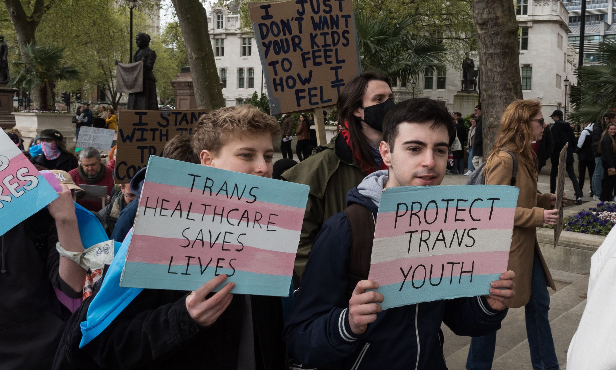 Activists hold signs calling for trans youth rights.