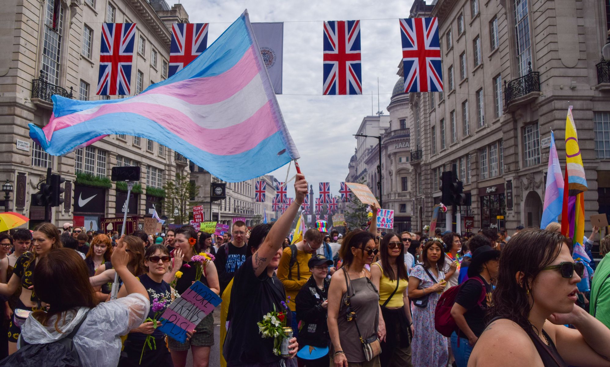 A crowd of people, with one waving a trans flag.