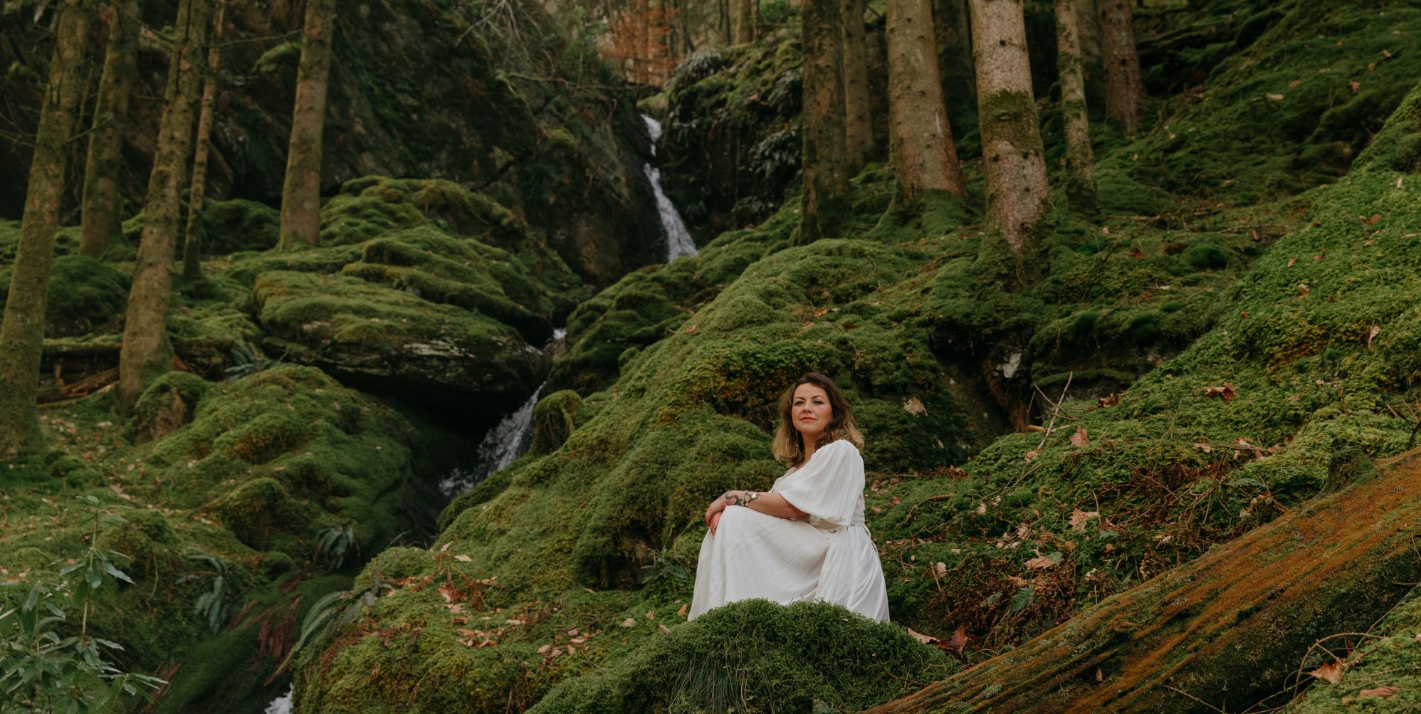 Charlotte Church in a white dress perching in the rainforest.