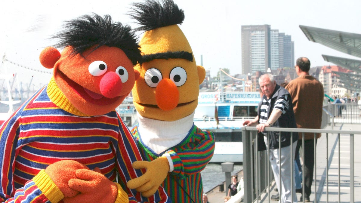 Bert and Ernie walking with looped arms on a pier.