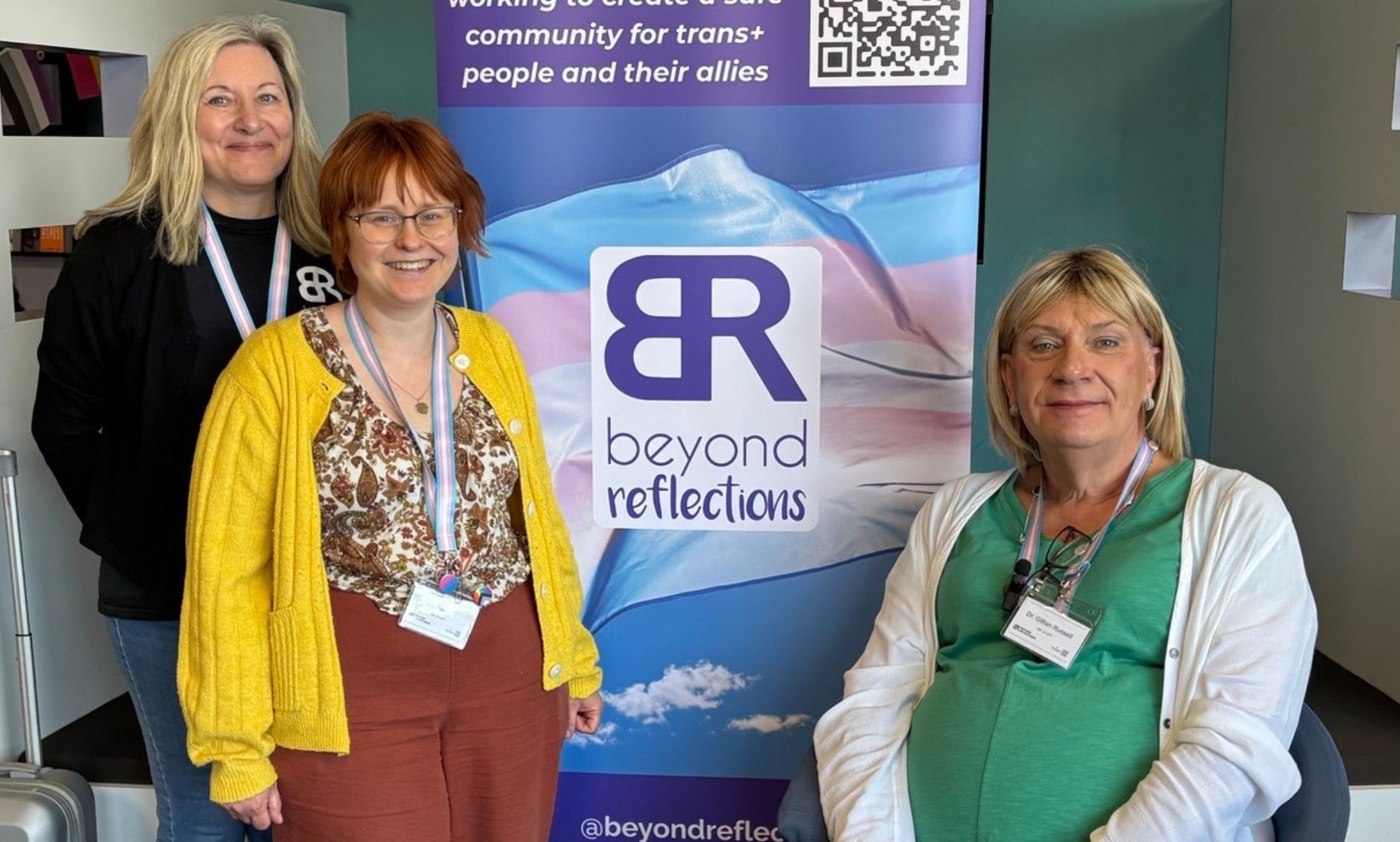 Three people stand by a Beyond Reflections banner, including Dr Gillian Russell (right)