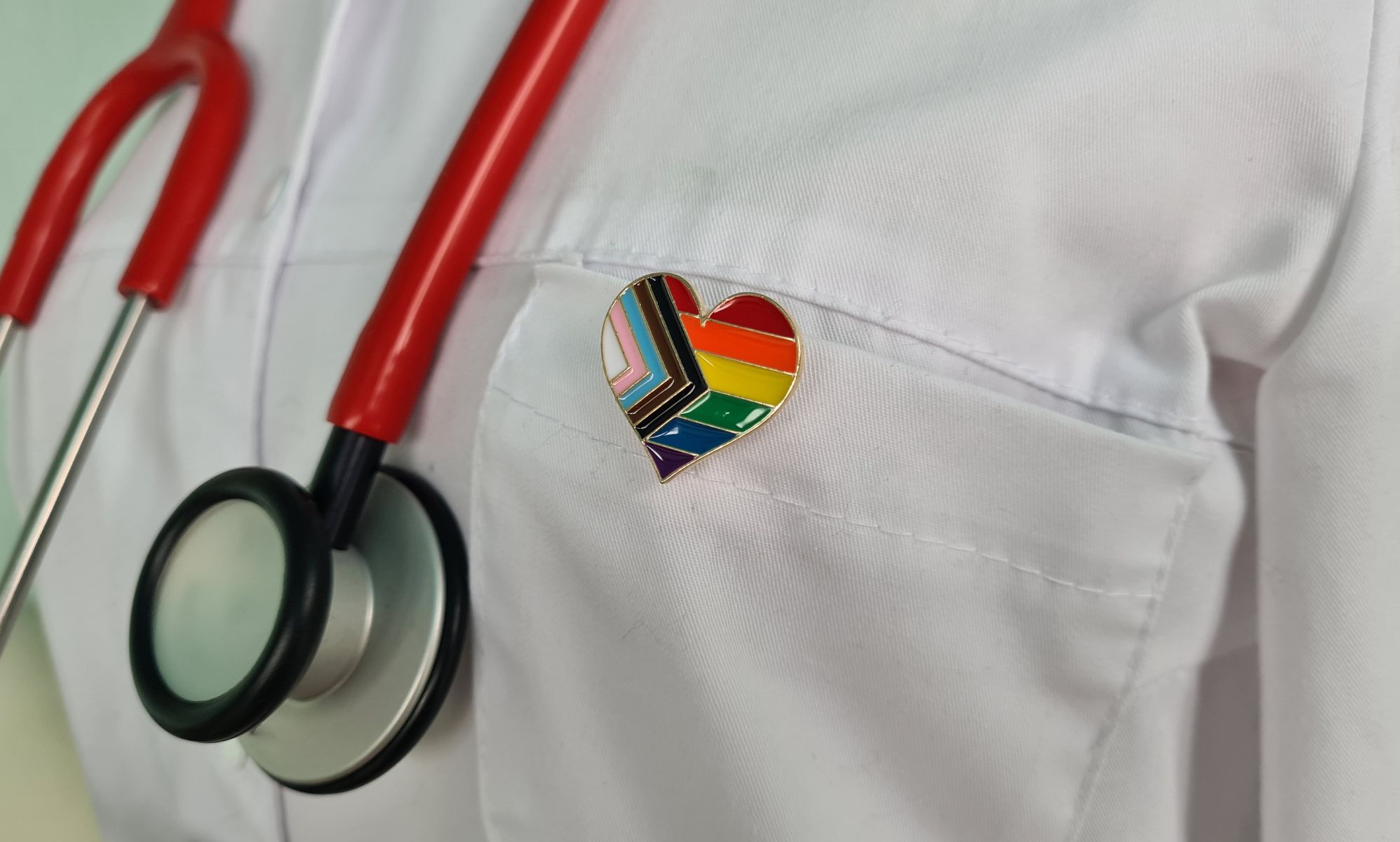 A doctor with an LGBTQ+ Pride pin on their jacket.