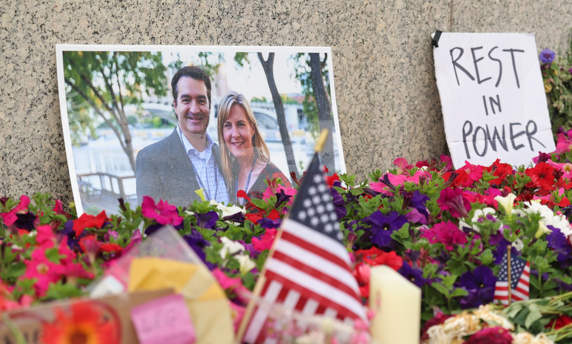 A set of flowers and signs mourning the loss of Melissa Hortman and her husband.