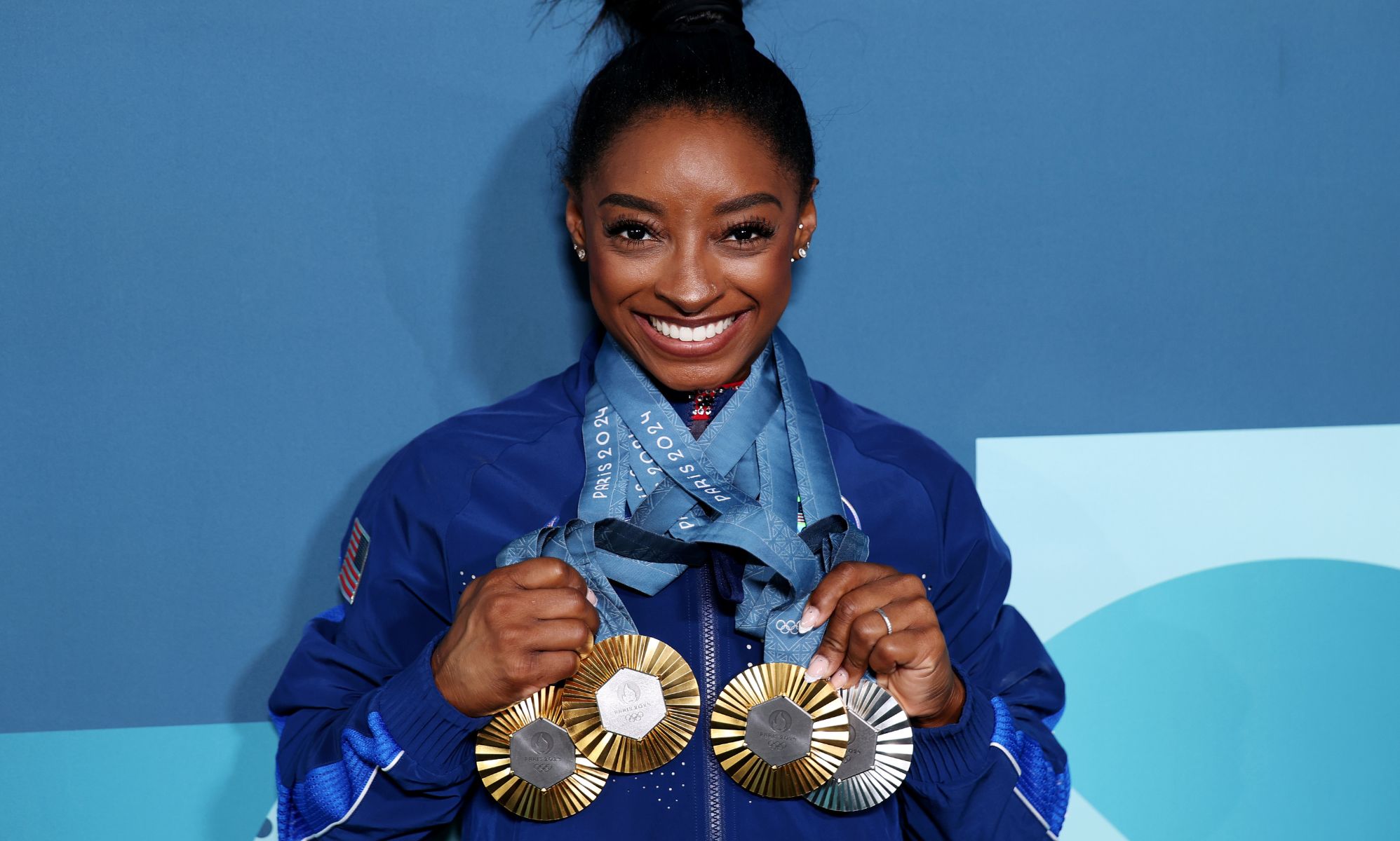 Simone Biles, pictured with three gold medals and a silver medal.