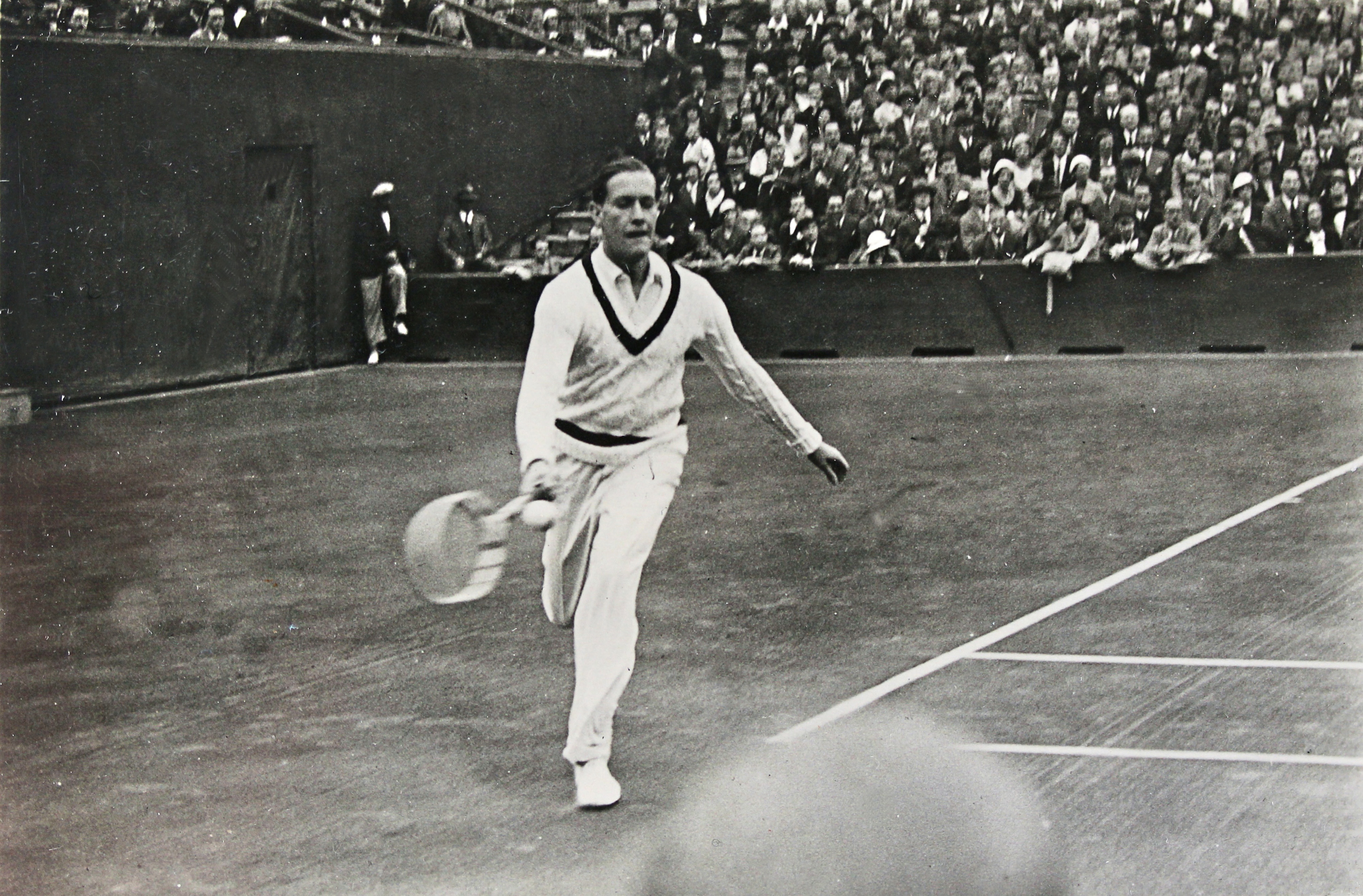 Gottfried Von Cramm in a black and white photo playing tennis.