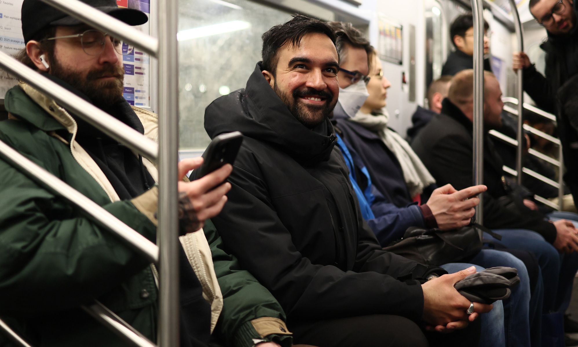Zahron Mamdani pictured smiling as he takes the New York subway.