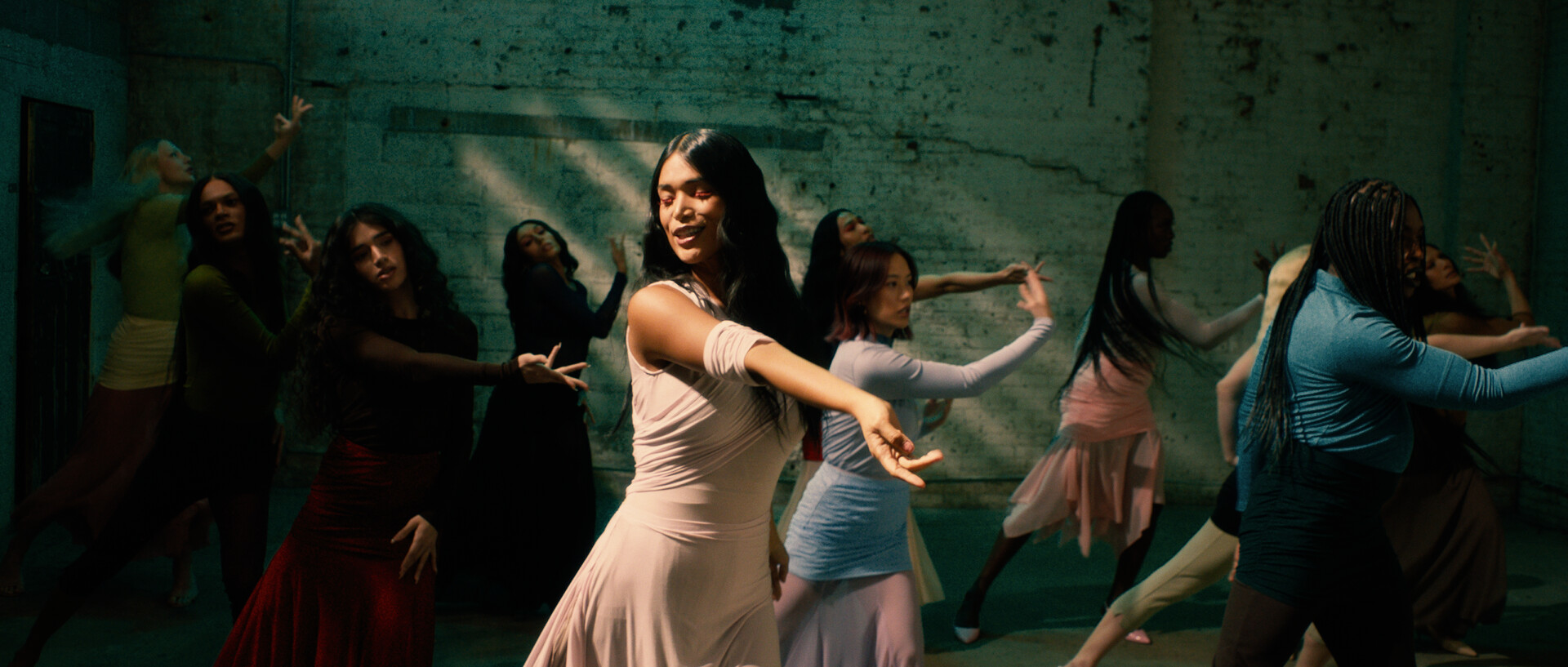 Dolls still: several women dancing, arms outstretched, wearing pastel clothes.