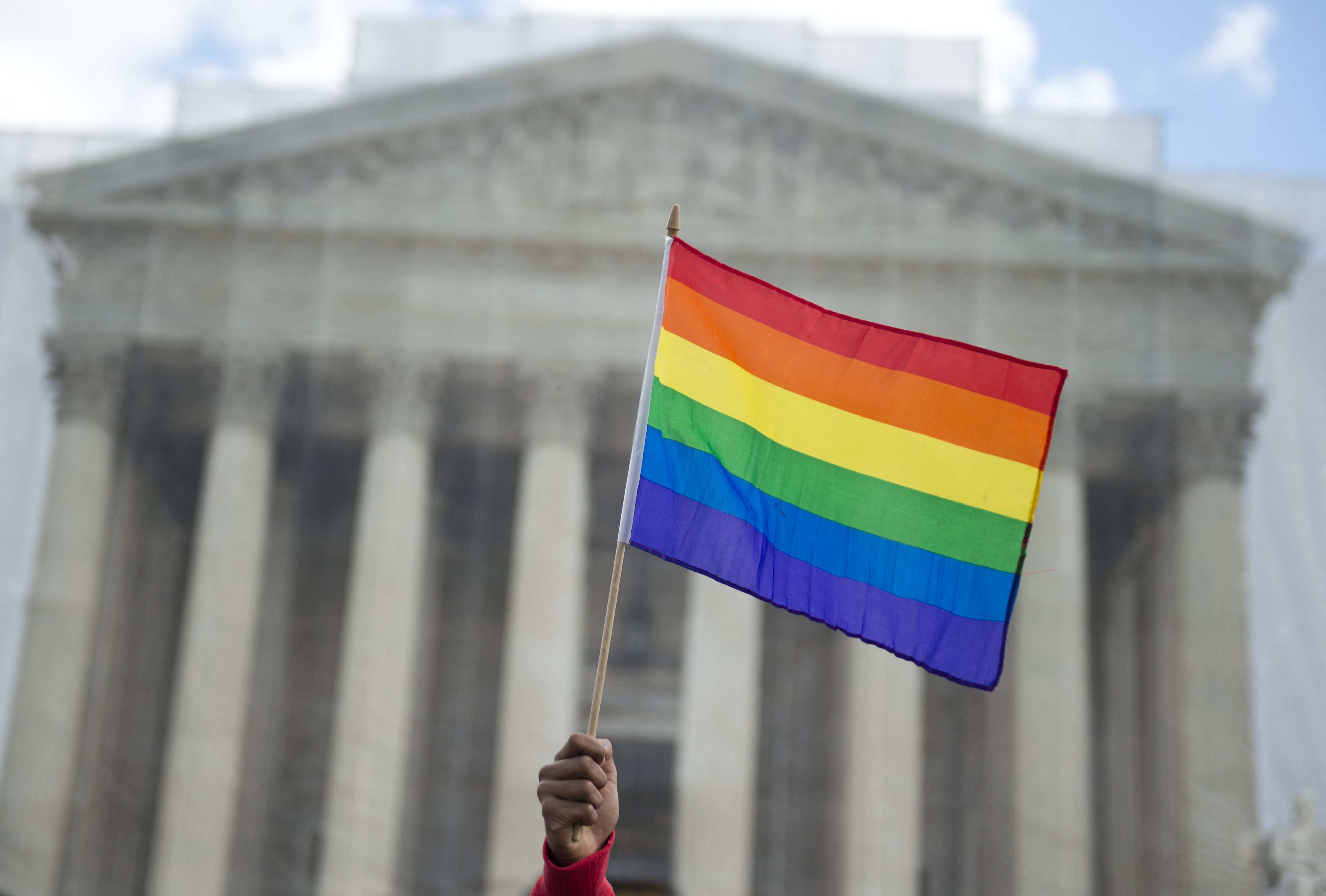 A same-sex marriage supporter waves a rainbow flag in front of the US Supreme Court
