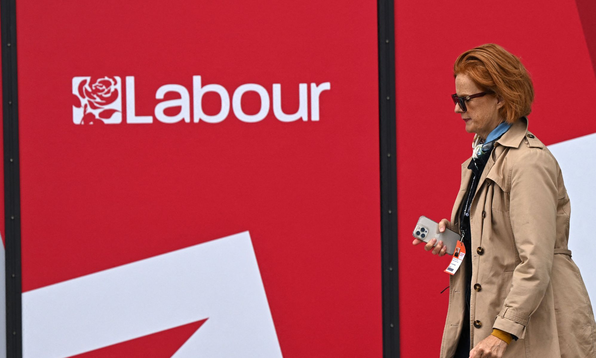 A person walking past a Labour Party logo on a wall.