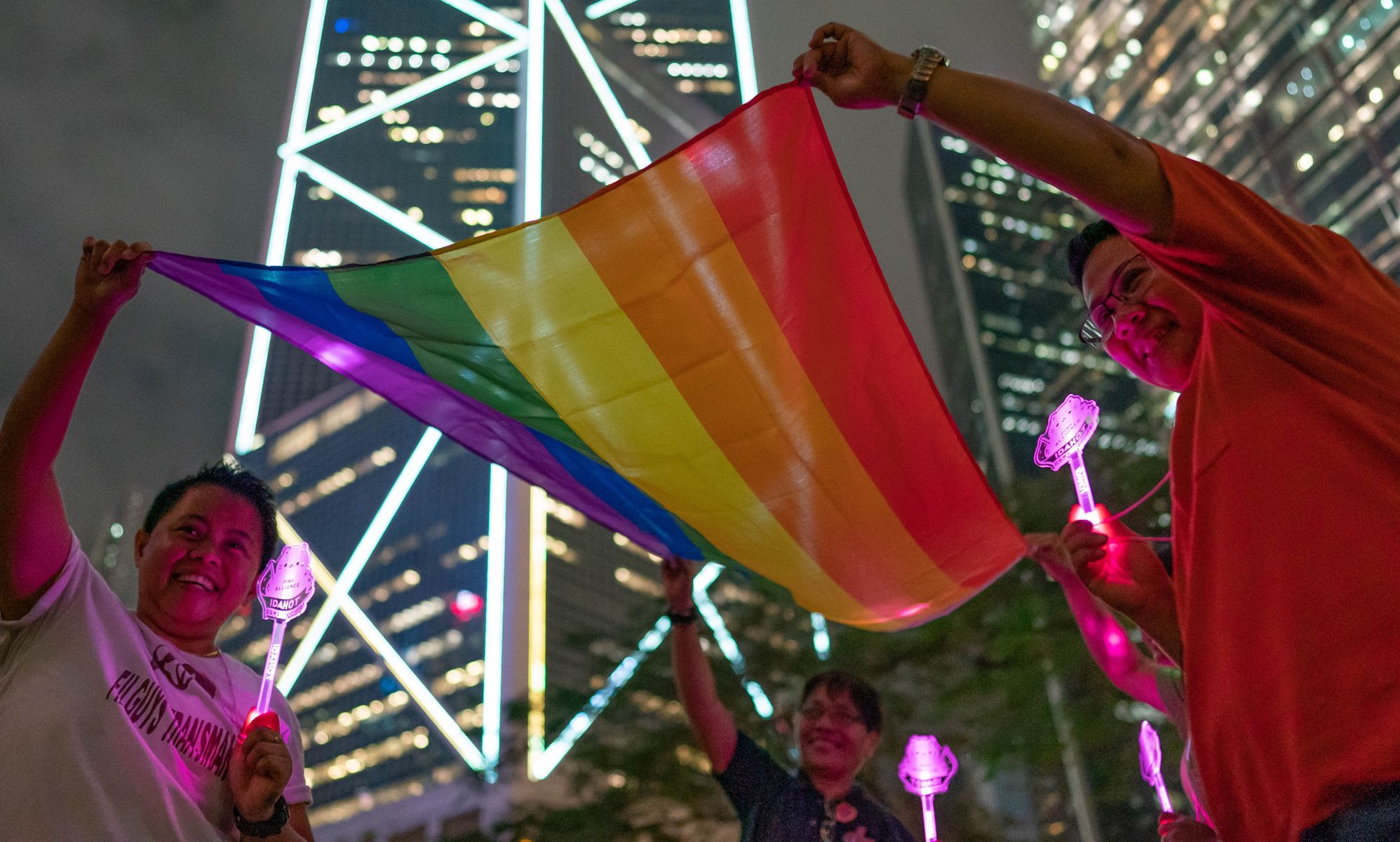 Four protestors holding an LGBTQ+ Pride flag in Hong Kong.