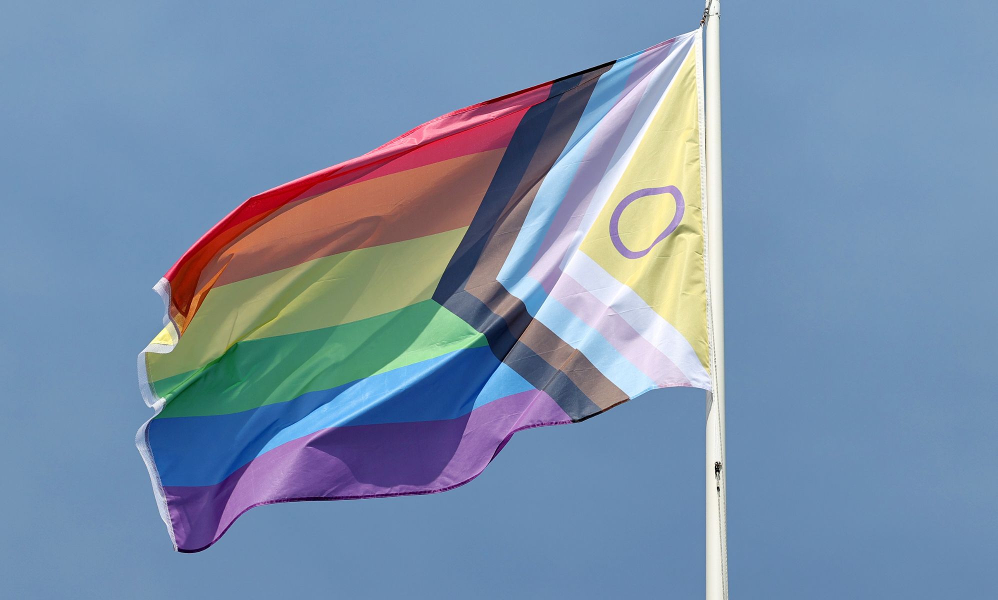 A Progress Pride flag on a flagpole.